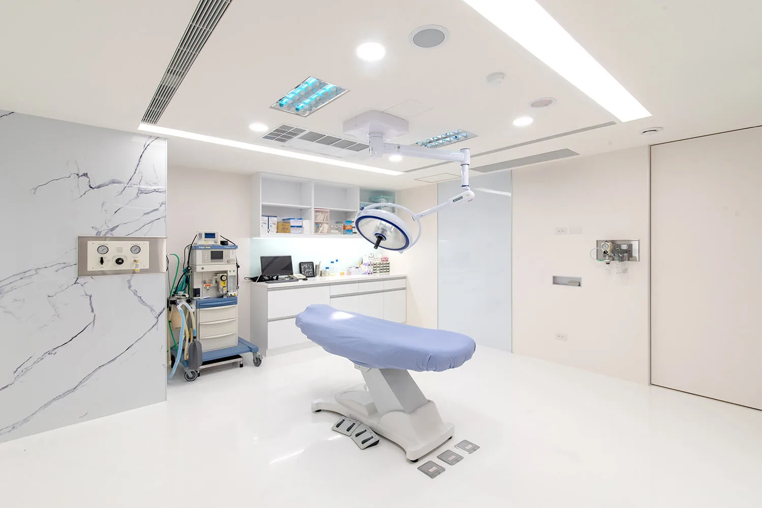 The operating room at Feng Hua Joint Clinic is equipped with surgical lights and anesthesia machines.